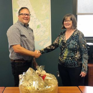 Ian Murdoch presenting a basket of local products to Anne Prich- ard on the occasion of her 20th anniversary as the Executive Director of Frontenac Business Services (formerly Frontenac Community Futures Development Corporation.